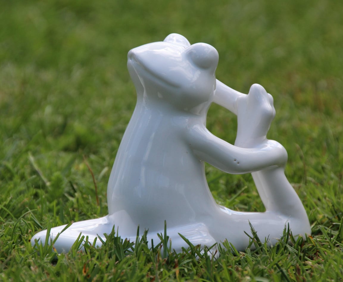 Keramikskulpture eines weißen Frosches der Yoga macht.