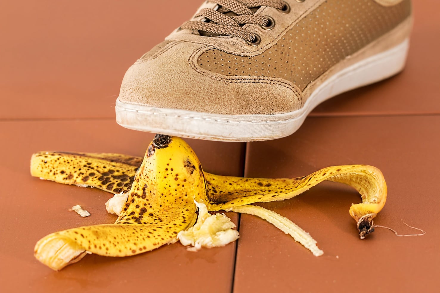 Ein mit einem Turnschuh bekleideter Fuß tritt auf eine Bananenschale.