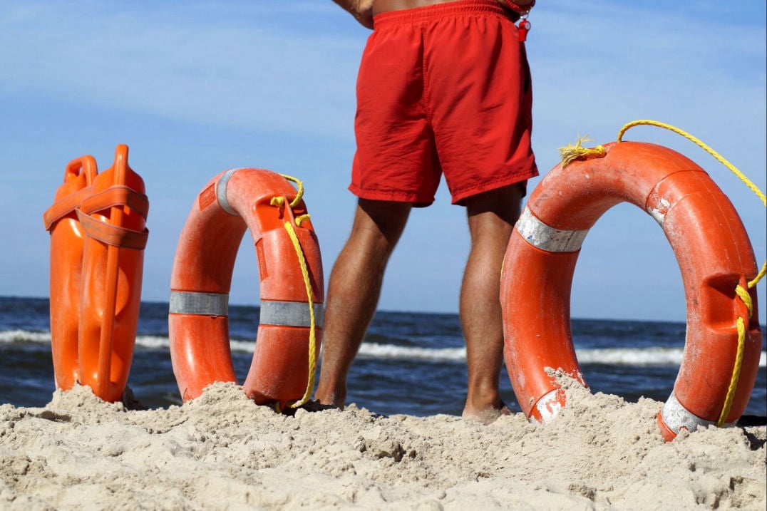 Ein Lebensretter zwischen Rettungsringen am Strand: Sicherheit auf Reisen. 