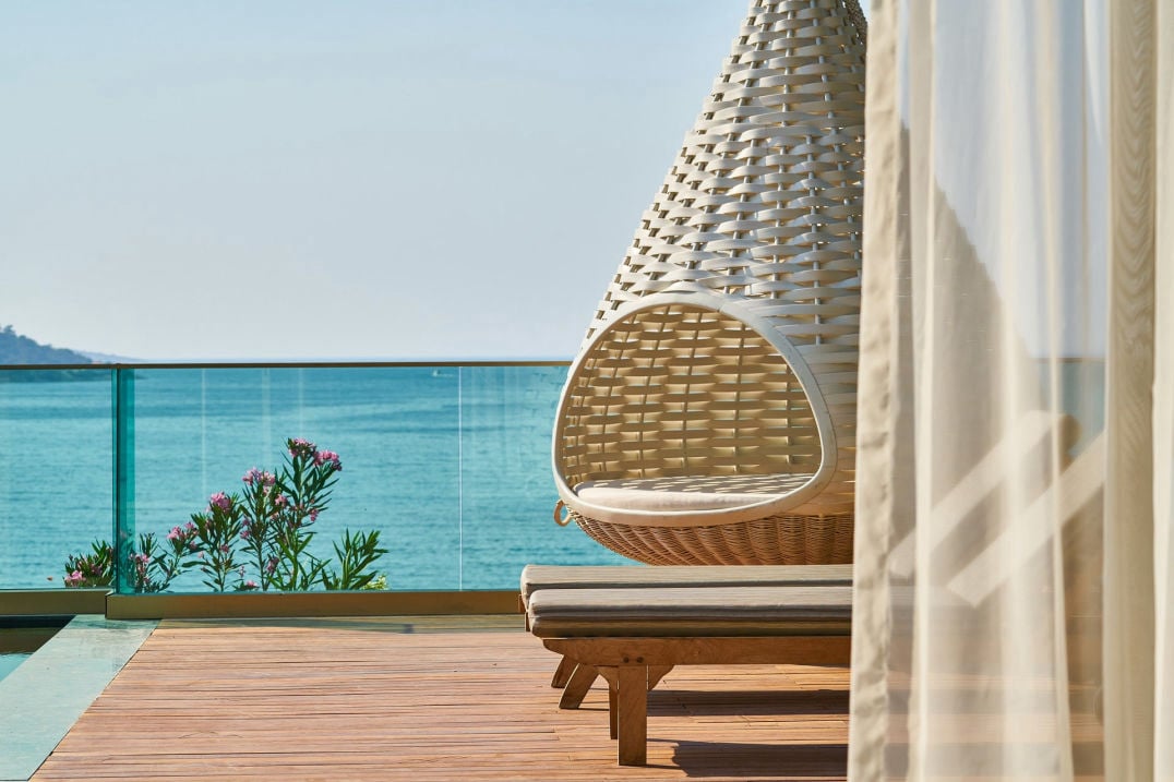 Hängestuhl auf einem Balkon mit Blick auf das weite, blaue Meer: Die Seele baumeln lassen.